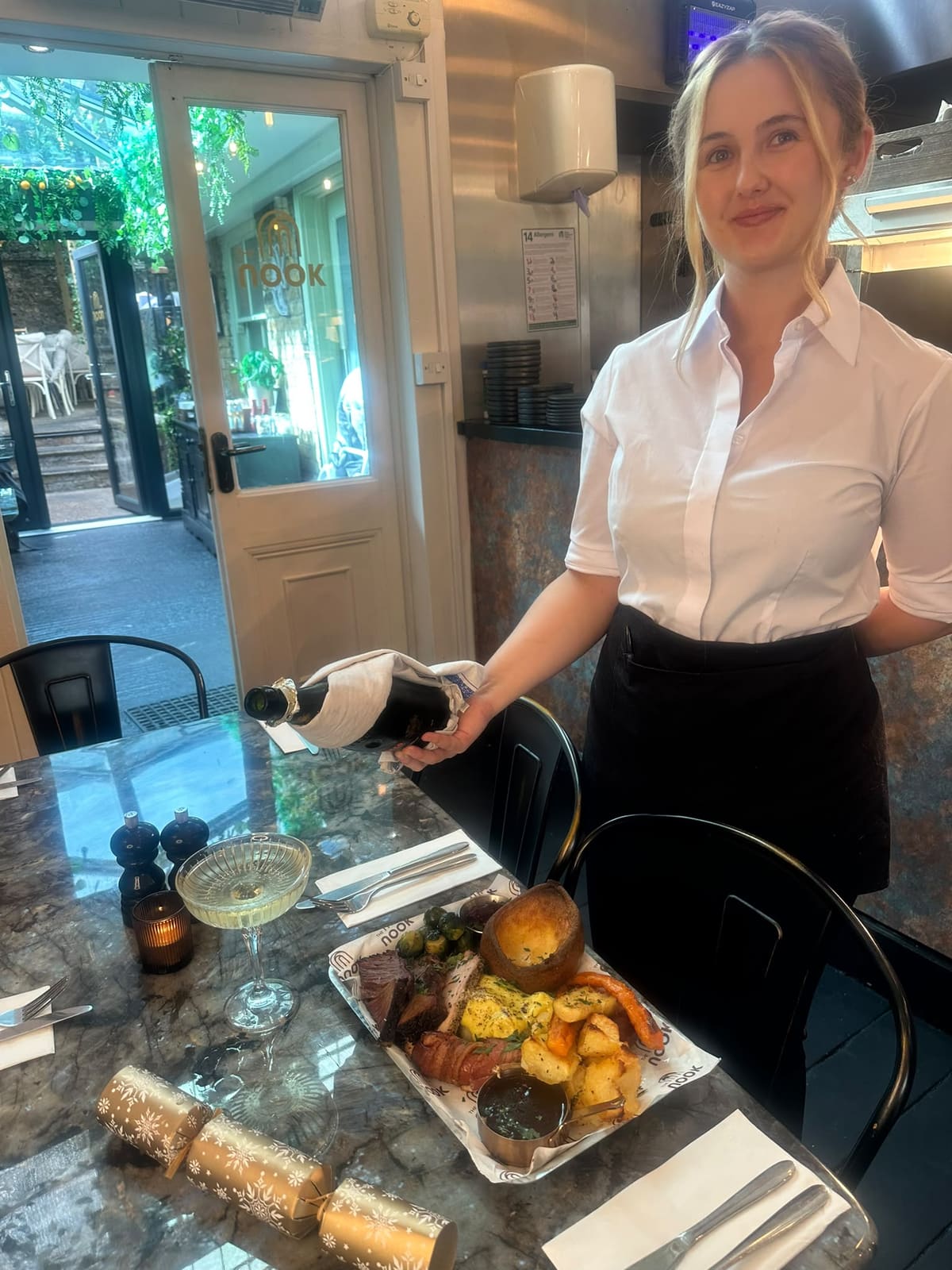 Waitress pouring prosecco at a table set for a Christmas party at The Nook restaurant in Dover